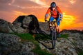 Cyclist Riding Mountain Bike Down Spring Rocky Hill at Beautiful Sunset. Extreme Sports and Adventure Concept. Royalty Free Stock Photo