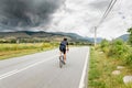 Cyclist riding towards storm clouds above mountains Royalty Free Stock Photo