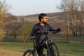 Cyclist in shorts and jersey on a modern carbon hardtail bike with an air suspension fork standing on a cliff against the backgrou