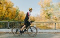Cyclist in sportswear rides bicycle in autumn park on river background. Man is walking on a bicycle in a beautiful autumn forest,