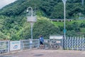 Cyclist standing on top of dam looking at river below