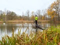 Cyclist stay at his trekking bike on small pond pier and watching swans