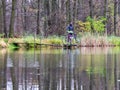 Cyclist stay at his trekking bike on small pond pier and watching swans