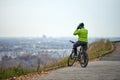 Cyclist on top of hill looking at cityscape, back view, copy space