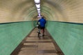 Cyclist walks his bike through tile lined underground subway pedestrian tunnel with lights