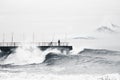 A cyclist watches from the pier the huge sea waves in a storm