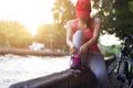 Cyclist woman sitting and tying shoeslace along the canal in sunset Royalty Free Stock Photo