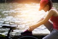 Cyclist woman sitting and tying shoeslace along the canal in sunset Royalty Free Stock Photo