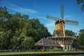 Cyclist and wooden yellow windmill next to wide tree-lined canal on sunset at Weesp.