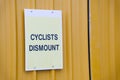 Cyclists dismount sign for safety of pedestrians on shared walk path Royalty Free Stock Photo