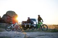 Friends are Resting on Pickup Offroad Truck after Bike Riding in the Mountains at Sunset. Adventure and Travel Concept