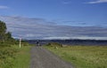 Cyclists heading down a gravel path on the Fife Coastal Path near to Tentsmuir Nature Reserve with a waypoint marker.