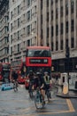 Cyclists and red double decker buses on a street in the City of London, UK, motion blur Royalty Free Stock Photo