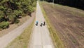 Cyclists ride along an empty road in a wooded area, aerial view, Top Down View