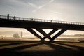 Cyclists ride in the morning in fog and sunrise over a bridge