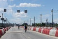 Cyclists ride the road on city bridge near plastic road barriers