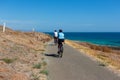 2 cyclists riding along the bike track at the beautiful Carrickalinga beach with rolling hills in the background on the Fleurieu P