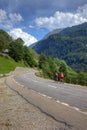 Mountain road landscape Swiss Alps mountains cyclists bicycle blue sky white clouds green forest trees summer travel highway rural Royalty Free Stock Photo