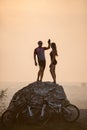 Cyclists standing on a large stone near mountain bikes