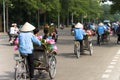 Cyclo pedicab driver wears conical hat on Hanoi street