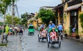 Cyclos carry tourists on street in Hoi An, Vietnam