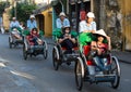 Cyclos carrying tourists on street in Hoi An, Vietnam