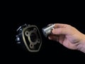 Cylinder and piston in a hand, on a black background. Piston system from a moped. Parts of a motor from a motorcycle, closeup