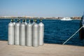 Cylinders with oxygen for divers. ten cylinders on sea dock. oxygen for divers on pier. Dark blue water and steel cylinders.