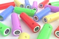 Cylindrical batteries of various colors on a white table. Compact batteries for electrical devices. Galvanic cells