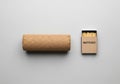 A cylindrical cork roll is placed next to an open box of matches on a light gray surface. The cork Royalty Free Stock Photo
