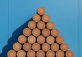 Cylindrical logs arranged in a triangular stack against a bright blue background. The logs, with Royalty Free Stock Photo