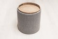 cylindrical padded stool upholstered with gray fabric. Stylish comfortable round padded stool with wooden top Royalty Free Stock Photo