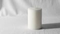 A cylindrical white candle is placed on a plain textured white surface Royalty Free Stock Photo