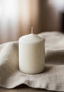 A cylindrical white candle with a pointed top and a visible wick stands on a textured, Royalty Free Stock Photo