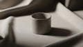 Cylindrical white ceramic cup is positioned centrally on a draped Royalty Free Stock Photo