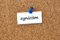 Cynicism. Word written on a piece of paper, cork board background