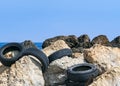 CYPRUS, KARAVAS, ALSANCAK - JUNE 10, 2019: Old car rubber tires on the rocks on seaside of the local beach