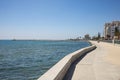 Cyprus, Larnaca city. Stone path around and above the sea. Port, beach, buildings, blue sky backdrop.