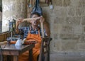 CYPRUS, NICOSIA - JUNE 10, 2019: Portrait of elderly man artisan sitting and and working in a local art gallery. Joiner working on