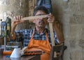 CYPRUS, NICOSIA - JUNE 10, 2019: Portrait of elderly man 60-75 years old artisan sitting and and working in local art gallery.