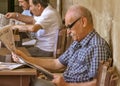 CYPRUS, NICOSIA - JUNE 10, 2019: Portrait of a handsome elderly man 70-80 years old reading a newspaper sitting at table in cafe