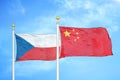 Czech and China two flags on flagpoles and blue cloudy sky