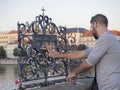 Czech Republic, Prague , September 8, 2018: Young man tourist touching the falling priest Saint John of Nepomuk on the bronze plaq