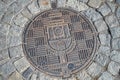 Czech sewer metal hatch with a pattern on the street with paving stones