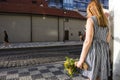 Czechia girl holding yellow flower bouquet and waiting at tramway station near PALLADIUM Shopping Center