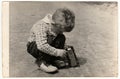 Vintage photo shows boy plays with toy car outdoors. Antique black and white photography. Royalty Free Stock Photo