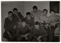 Vintage photo shows soldiers pose in barracks. One of them plays the guitar. Black and white antique photo.