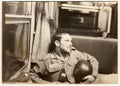 Vintage photo shows man with bottle of wine sits in railway carriage. Black and white antique photo.