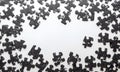 Scattered black puzzle pieces with a glossy finish are arranged around the edges of a white background Royalty Free Stock Photo