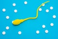 3D anatomical model of sperm cell or spermatozoon is on blue background surrounded by white pills as ornament polka dots. Photo co